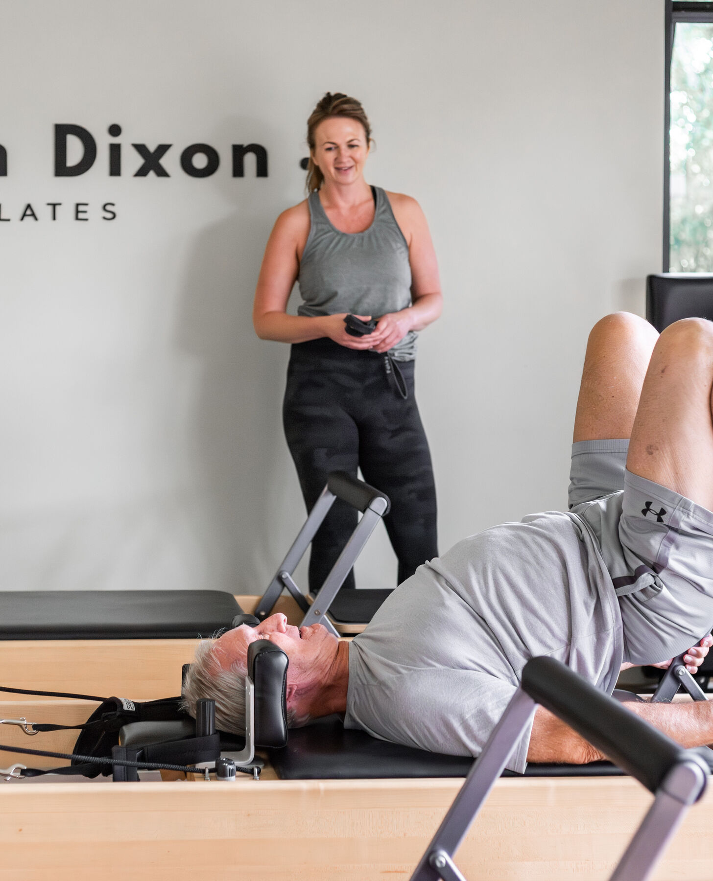 Helen Dixon smiling while coaching a client on the Reformer